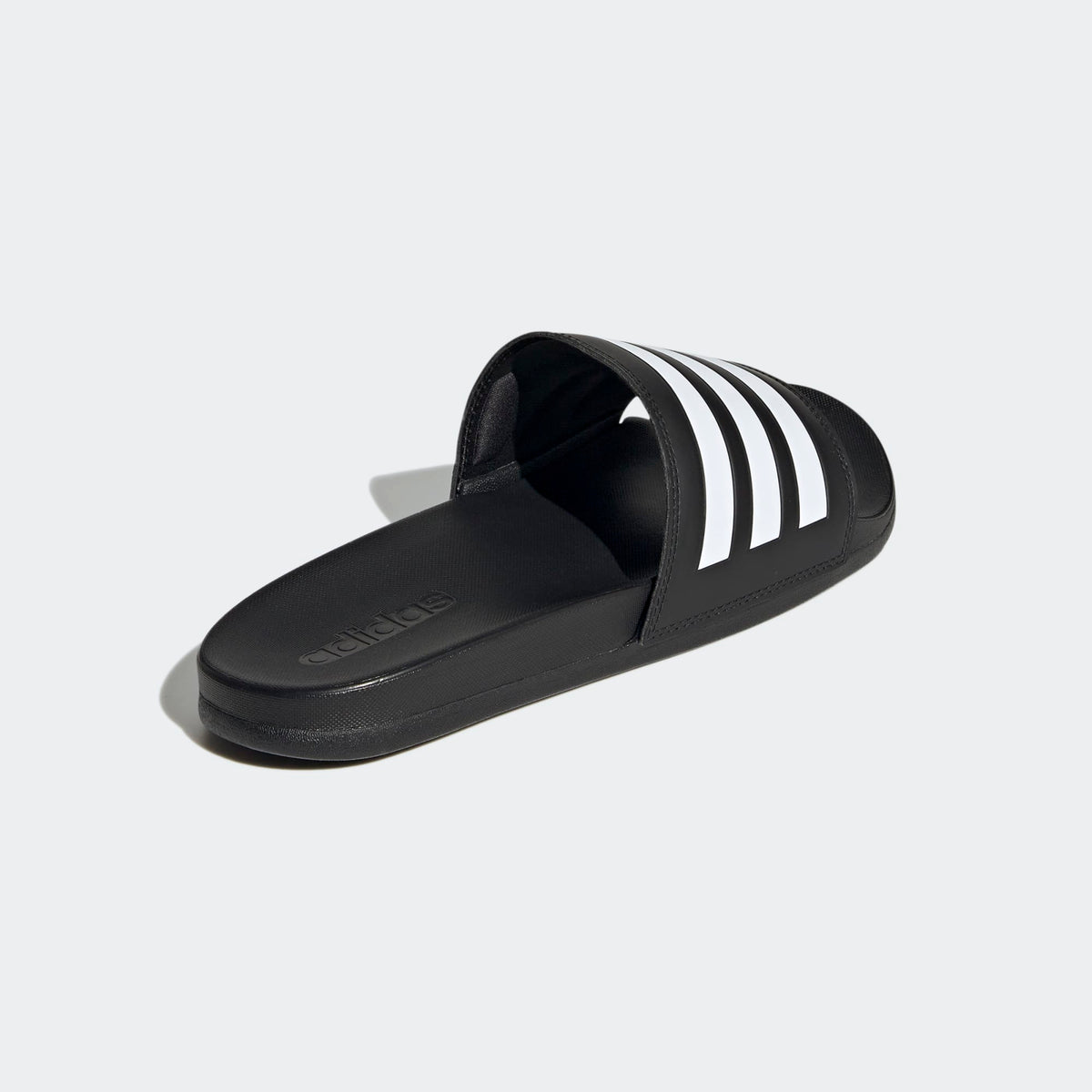 Black slide sandal with white stripes on a light gray background