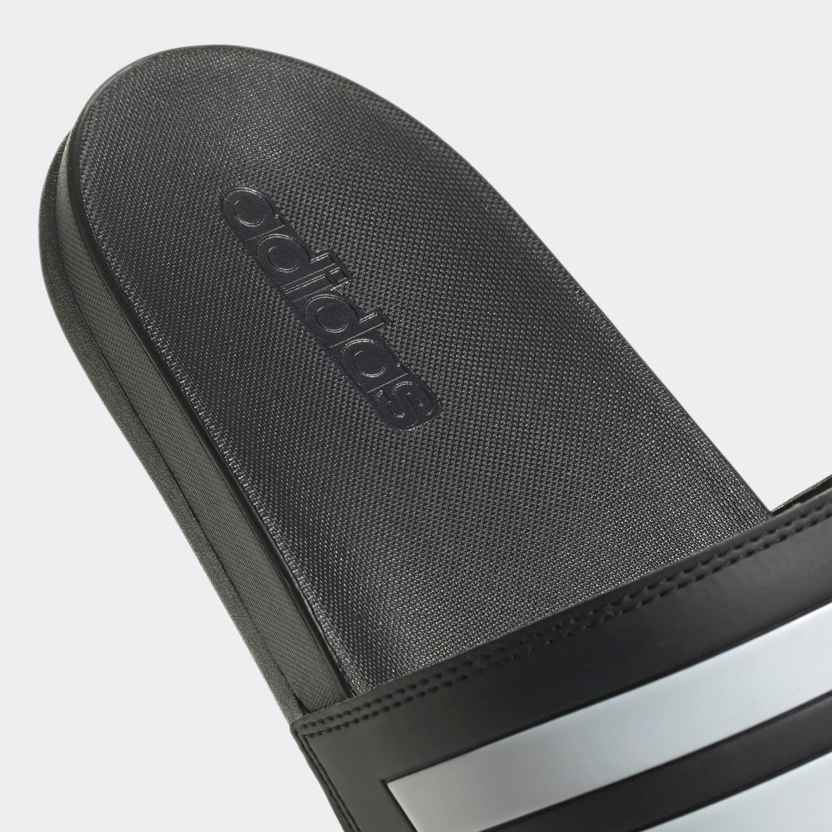 Black Adidas sandal with logo on a light gray background